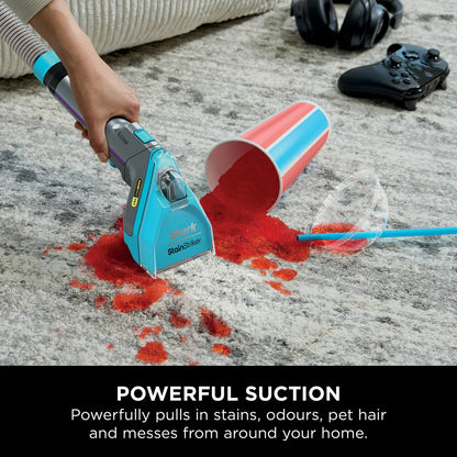 Front view of the white and deep navy Shark StainStriker HairPro PX250UKT spot cleaner sitting on a beige living room rug beside its attached hose and pet hair extraction tool.