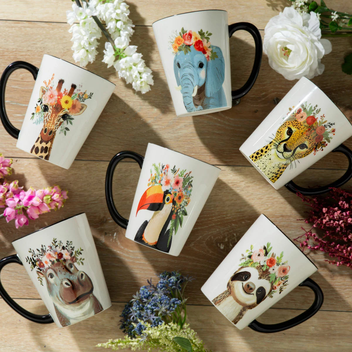A set of six Signature Housewares 483ml stoneware mugs featuring colourful illustrations of a toucan, giraffe, hippo, elephant, cheetah, and sloth wearing hipster accessories, displayed on a clean kitchen counte