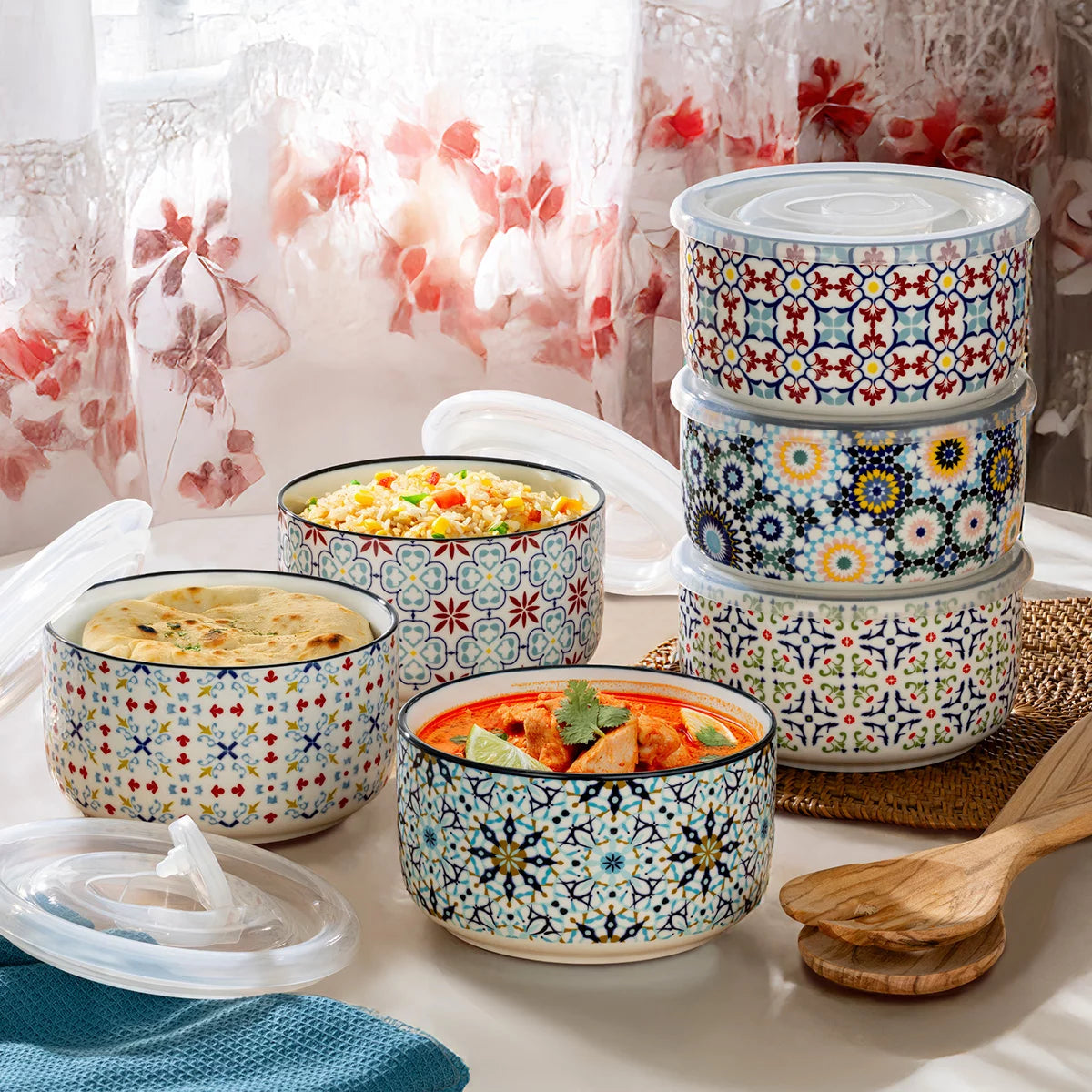 The Signature Stoneware Bowls with Lids 6-Pack displayed on a table, showcasing their colorful patterned exteriors and matching storage lids.