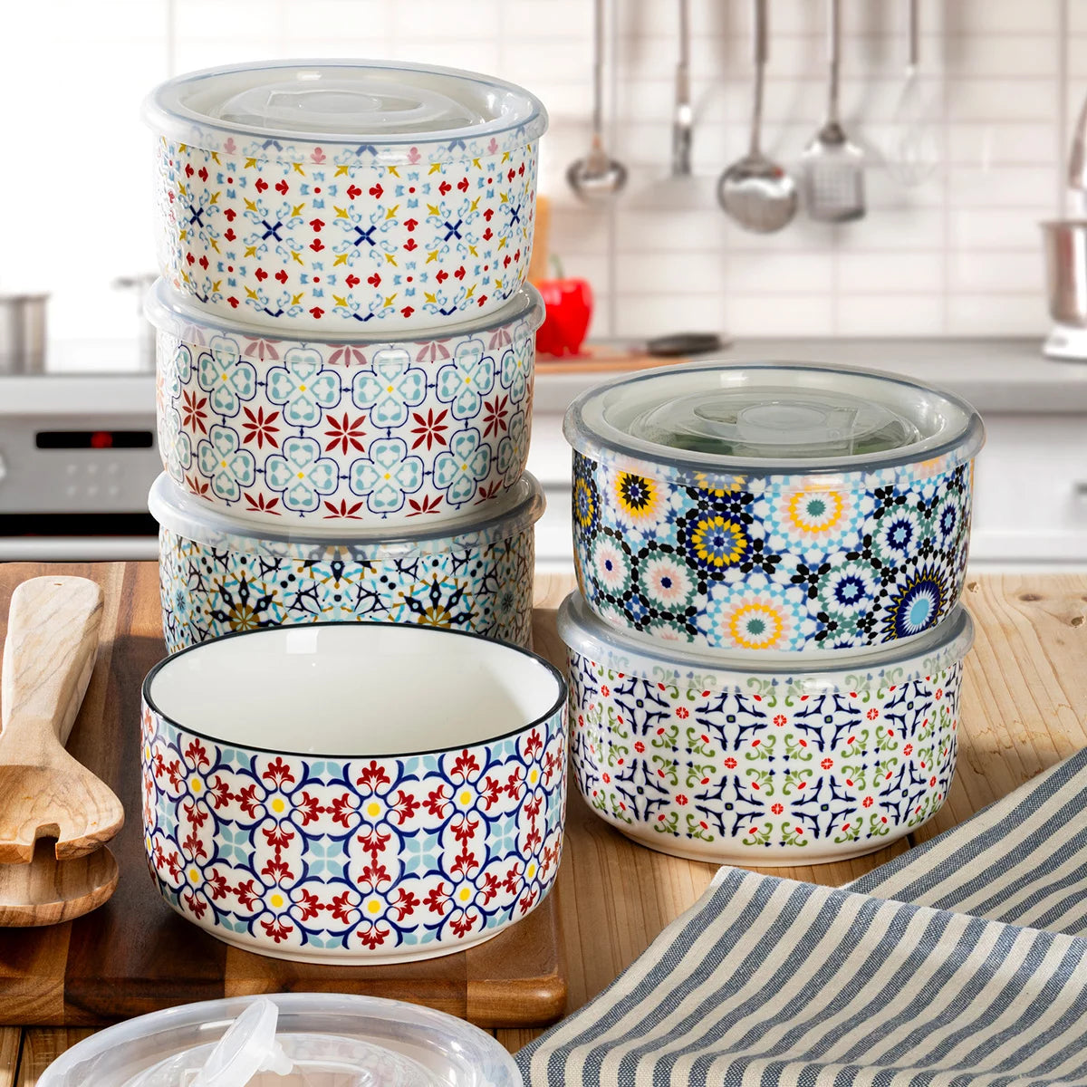 The Signature Stoneware Bowls with Lids 6-Pack displayed on a table, showcasing their colorful patterned exteriors and matching storage lids.