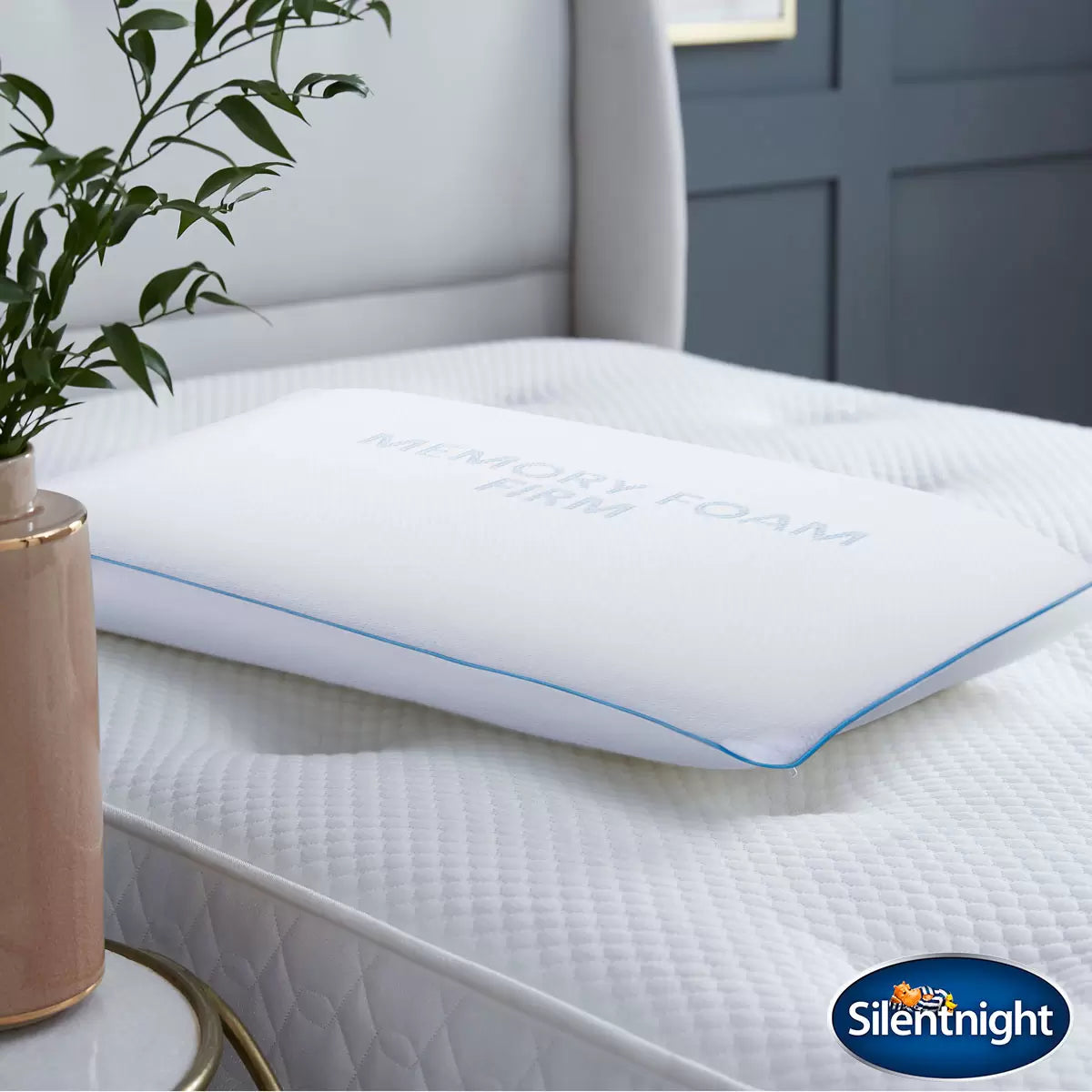 White Silentnight Impress firm memory foam pillow with textured removable cover shown at a three-quarter angle on a modern bed.