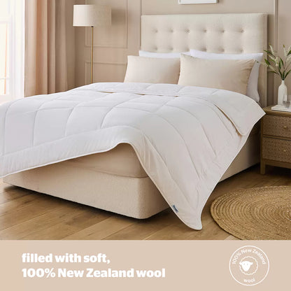 Flat-lay image of the white Silentnight natural wool double duvet with soft 100% cotton stitching resting on a neatly dressed wooden bed.