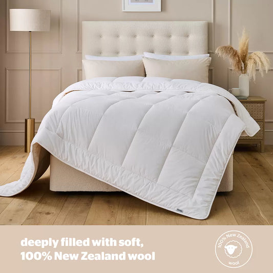 Angle view of a thick white Silentnight natural wool heavyweight duvet draped over a modern wooden bed frame in a cozy bedroom setting.
