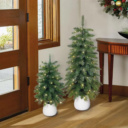 Pair of 2ft and 3ft silver glitter potted artificial trees with glowing warm white twinkling LED lights sitting on a white porch threshold.