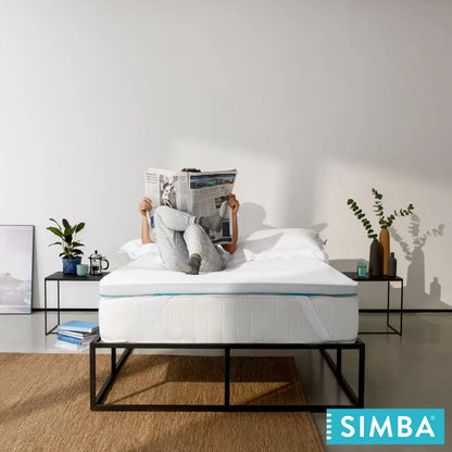 White Simba Hybrid Essential Mattress Topper featuring blue accent trim and corner straps displayed on a contemporary bed.