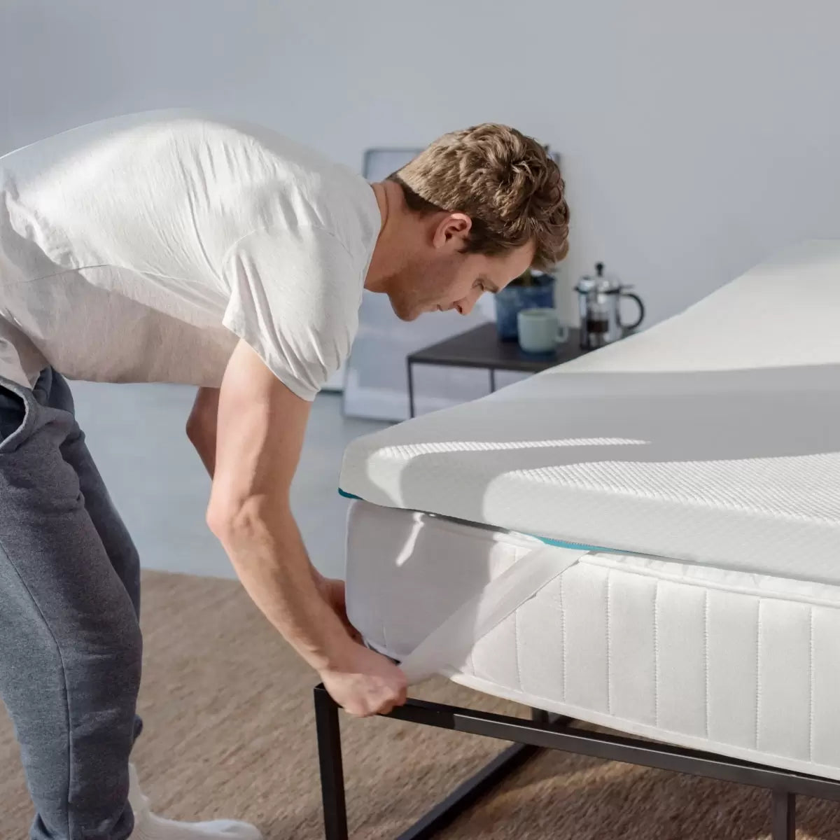 White Simba Hybrid Essential Mattress Topper featuring blue accent trim and corner straps displayed on a contemporary bed.