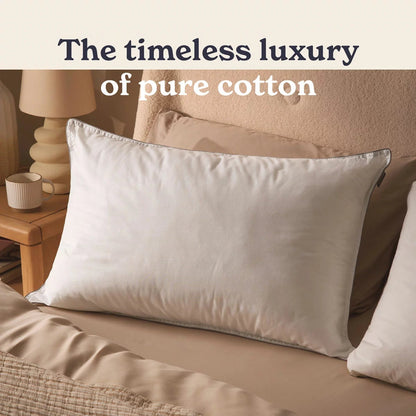 Crisp white Sleepeezee Sumptuous Cotton Pillow with neat piped edges resting on a pristine white bed sheet in a modern bedroom setting.