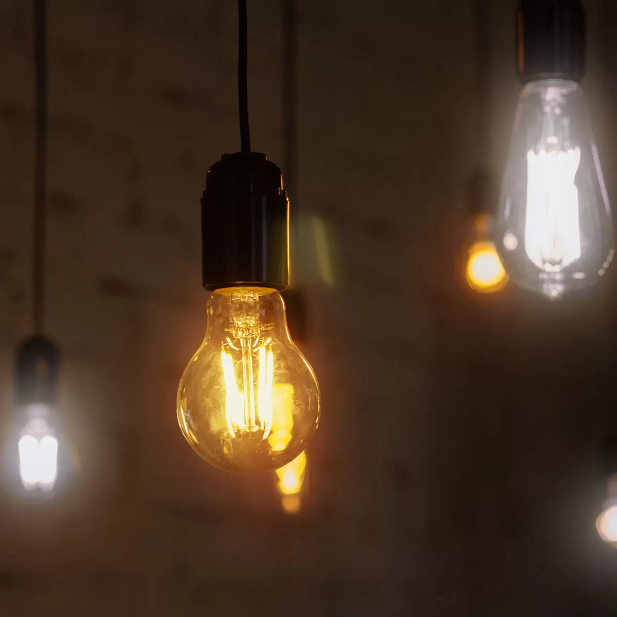 A pair of 4lite WiZ B22 smart LED lightbulbs showing amber-tinted glass and visible glowing filaments against a neutral studio background.