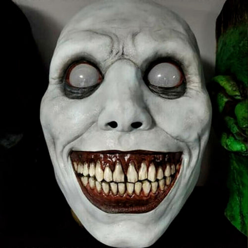 White smiling demon Halloween mask made of flexible latex featuring stark black eye sockets, a wide eerie grin, and red teeth displayed against a neutral background.