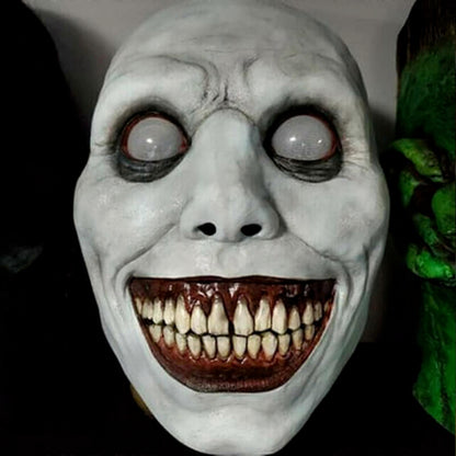 White smiling demon Halloween mask made of flexible latex featuring stark black eye sockets, a wide eerie grin, and red teeth displayed against a neutral background.