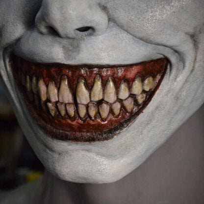 Front view of a creepy ashen gray smiling demon latex mask featuring oversized eyes and a wide gaping mouth.