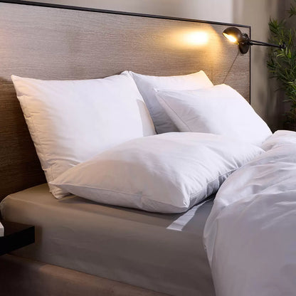 Stack of four white Snuggledown Clusterdown Synthetic Pillows showing crisp self-piped cotton edges on a wooden bedroom chest.