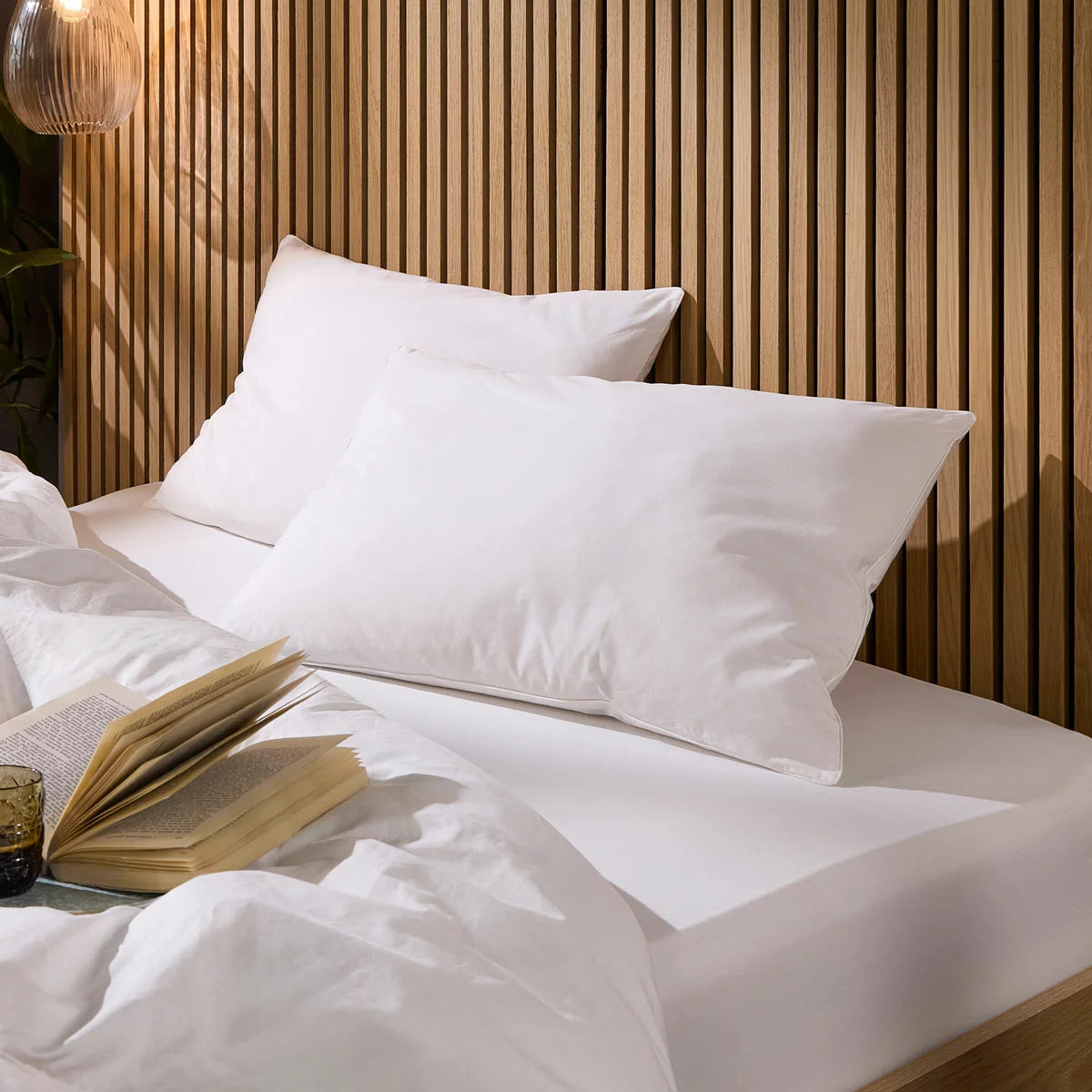 Pair of white Snuggledown Soft As Down pillows with elegant piped edges styled on a crisp hotel-style bed.
