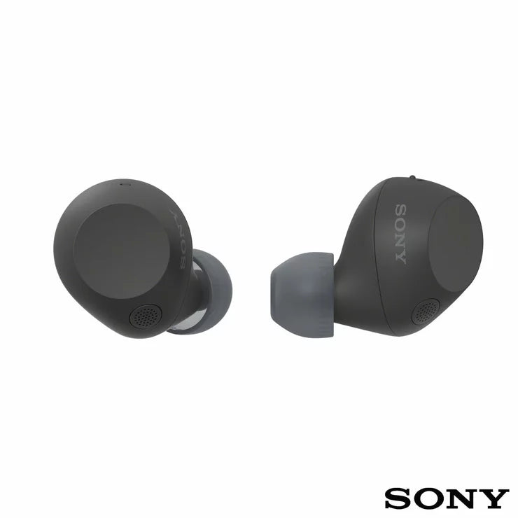 Front angle view of Sony WF-C710N Glass Blue wireless noise cancelling earbuds sitting beside their open charging case on a minimalist wooden desk.