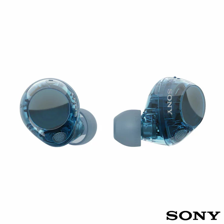 Front angle view of Sony WF-C710N Glass Blue wireless noise cancelling earbuds sitting beside their open charging case on a minimalist wooden desk.