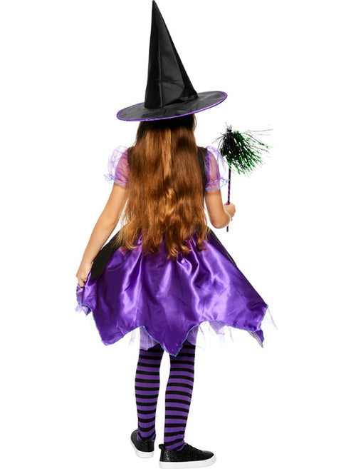 Toddler wearing a purple and black Spell Casting Cutie witch costume with a matching pointed hat outdoors.