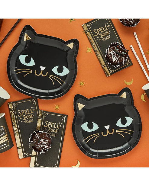 Pack of eight round black cat paper plates for Halloween parties displayed on a wooden table setup.