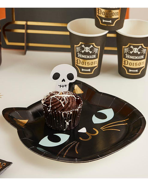 Pack of eight round black cat paper plates for Halloween parties displayed on a wooden table setup.