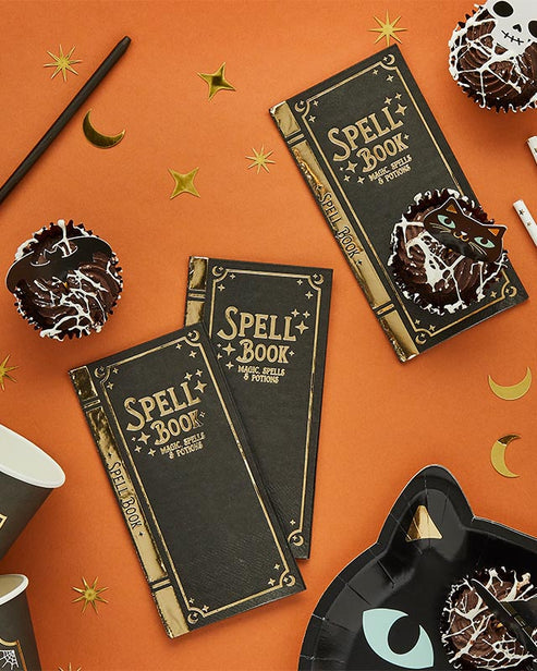 Flat lay view of twelve Spell Yeah! ancient spellbook-themed folded paper party napkins arranged on a dark wooden party table.