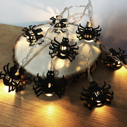 Creative spider LED string lights glowing with a spooky ambiance along an outdoor patio wall.