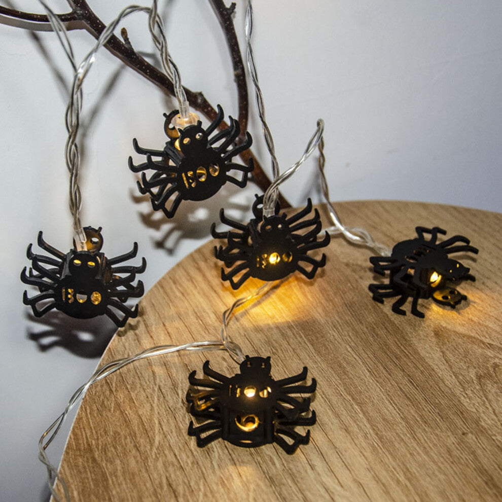 Creative spider LED string lights glowing with a spooky ambiance along an outdoor patio wall.