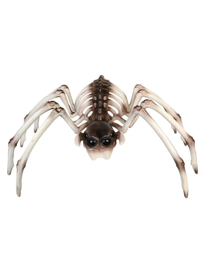 A Smiffys brown and white spider skeleton Halloween prop sitting on a dark wooden table, surrounded by artificial cobwebs under dim atmospheric lighting.
