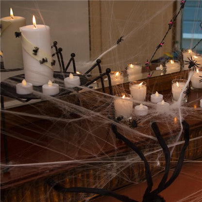 White stretchable synthetic spider web draped across a dark wooden doorframe with four small black plastic spiders embedded in the strands.