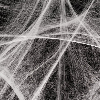 White stretchable synthetic spider web draped across a dark wooden doorframe with four small black plastic spiders embedded in the strands.