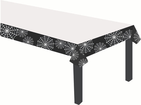 Flat lay view of a rectangular spider web printed paper tablecover spread over a party table topped with Halloween treats.