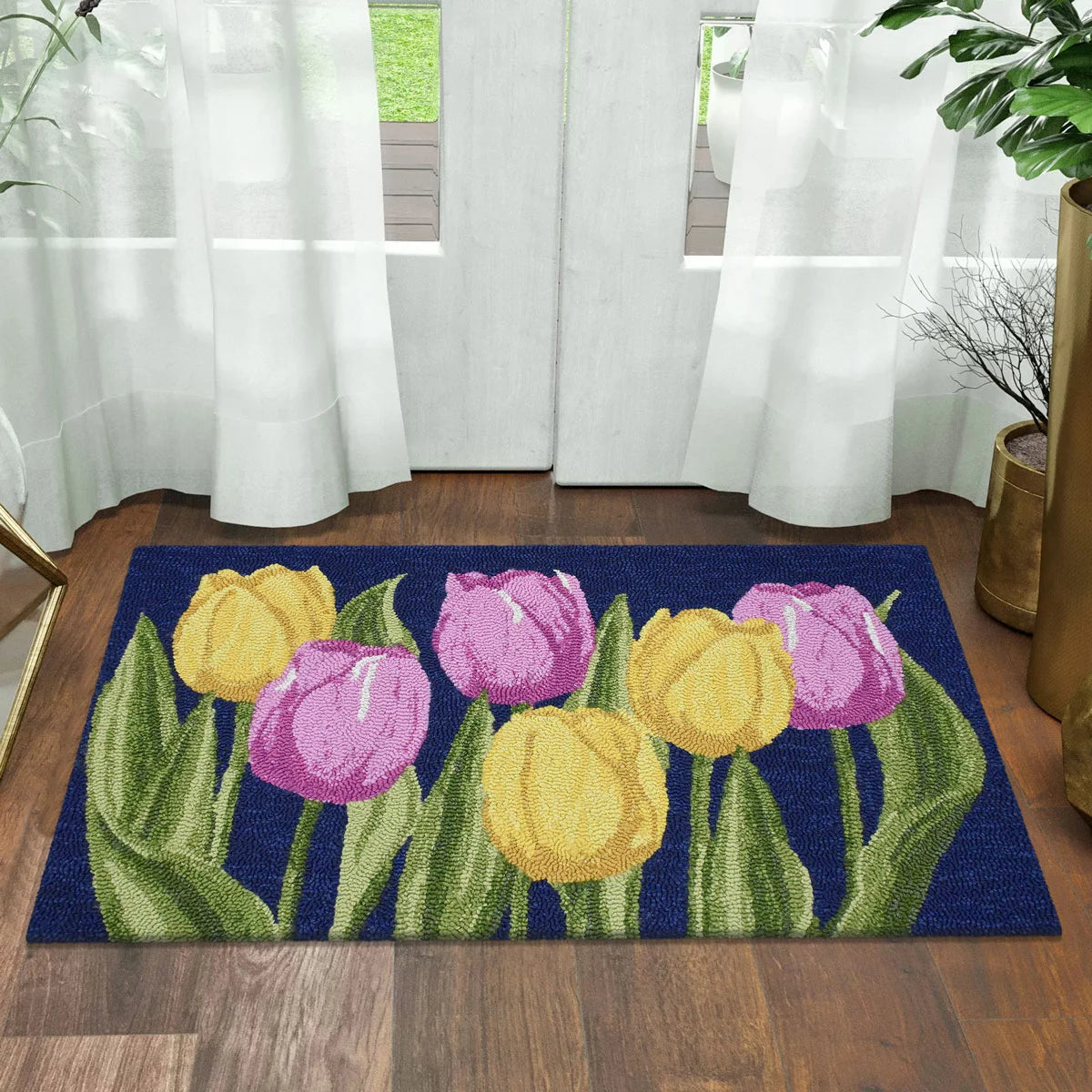 Top-down view of the colourful hand-hooked spring accent rug with textured floral motifs on a light hardwood entryway floor.