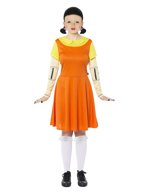 Adult wearing the orange pinafore dress and yellow collared shirt Squid Game doll costume standing in a full-length front view pose.
