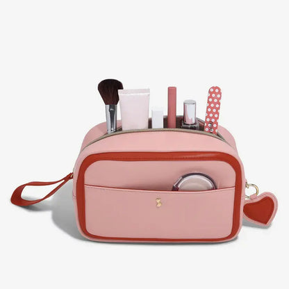 Stackers Heart Cosmetic Case in soft faux-leather, displayed next to a gold-accented mirror and beauty essentials on a clean white vanity surface.