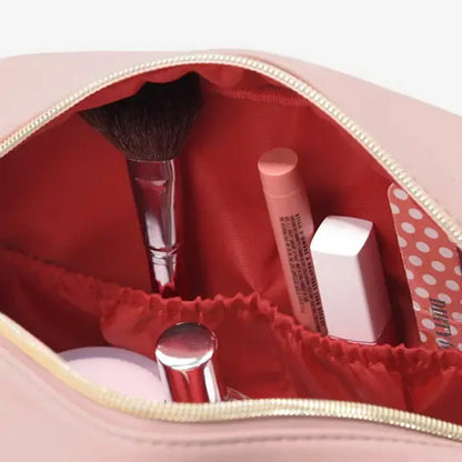 Stackers Heart Cosmetic Case in soft faux-leather, displayed next to a gold-accented mirror and beauty essentials on a clean white vanity surface.
