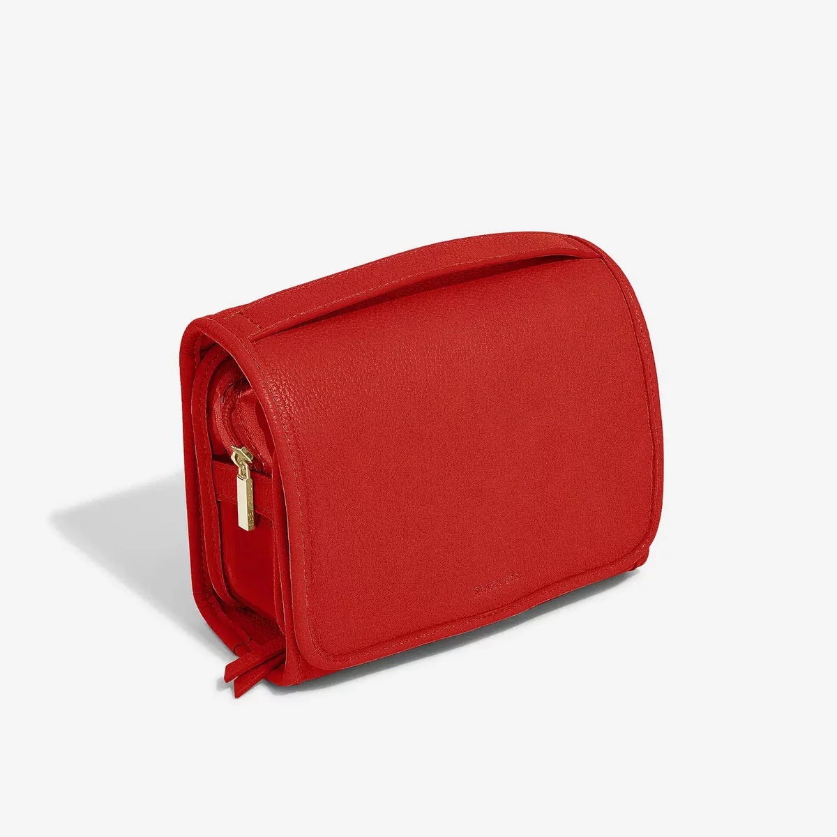 Vibrant red Stackers Small Hanging Washbag shown in an open, hanging position on a bathroom hook, showcasing the internal zipped compartments and clear pouch.