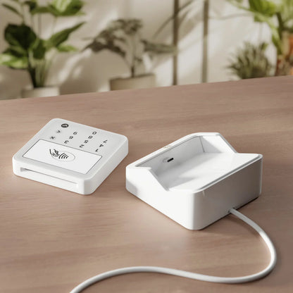 SumUp Solo Lite card reader mounted upright on its sleek black charging station against a clean retail countertop backdrop.