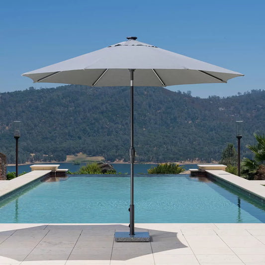 Grey SunVilla 10ft Solar LED Market Umbrella with lit ribs and an octagonal Outdura fabric canopy on a modern patio.