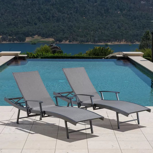 Set of two SunVilla grey aluminium wave sun loungers with Phifertex sling fabric, adjustable reclining backrests, folding arms, and hidden wheels positioned beside a modern outdoor swimming pool.