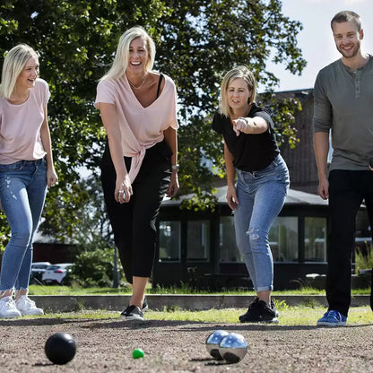A Sunsport Boules Petanque set featuring six polished and black metal balls, a wooden jack, and a measuring tape arranged neatly next to an open aluminium storage case on a grassy garden lawn.