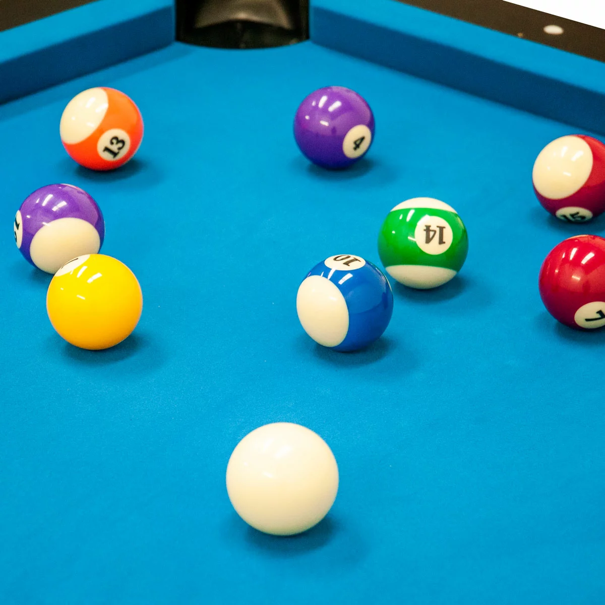 Three-quarter overview of the black Sure Shot Elite Pro 7ft Pool Table showing its green cloth surface, polished chrome corner caps, and large adjustable feet set on a grey modern flooring.