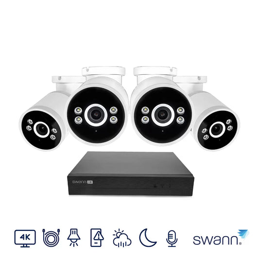 Front view of the black and white Swann 4K NVR box sitting alongside four outdoor bullet cameras with integrated LED spotlights on a clean surface.