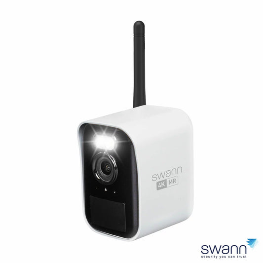 Compact white Swann MaxRanger4K Mini wireless security camera with integrated spotlight and black lens face mounted outdoors on a brick structure.