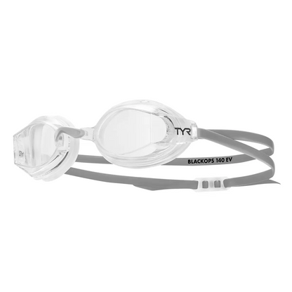 Three pairs of low-profile TYR adult swim goggles with clear anti-fog lenses and black silicone straps arranged neatly on a pool deck.