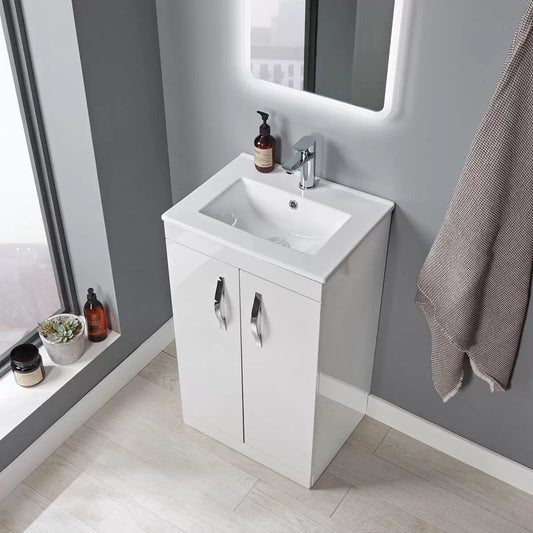 Front angle view of the Tavistock Vesta gloss white 51cm floor mounted vanity unit with integrated white ceramic basin and sleek chrome handles in a modern tiled bathroom setting.