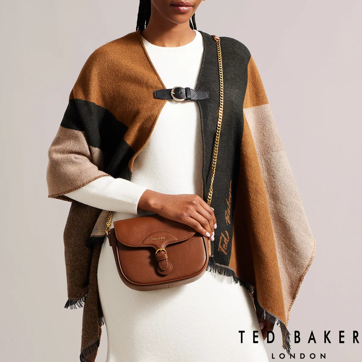 Ted Baker Esia black leather crossbody bag with gold-tone buckle detail and adjustable branded webbing strap.