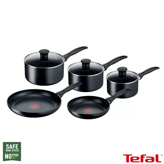 Tefal 5-piece black induction cookware set with lidded saucepans and frying pans with red Thermo-Signal spots arranged on a dark granite kitchen island.