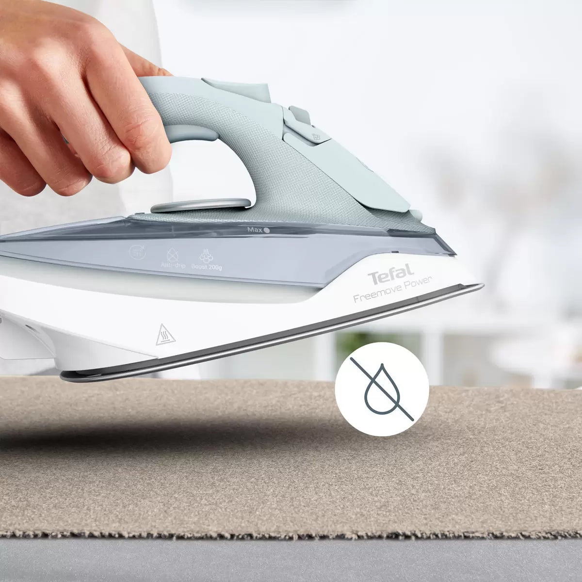 Tefal Freemove Power cordless steam iron FV6642G0 resting on its horizontal charging base with lock system on an ironing board.