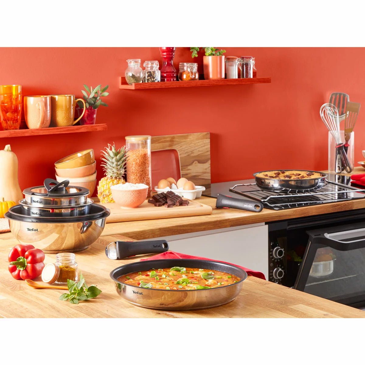 A 13-piece Tefal Ingenio Emotion stainless steel cookware set neatly stacked in a cupboard, demonstrating space-saving convenience.