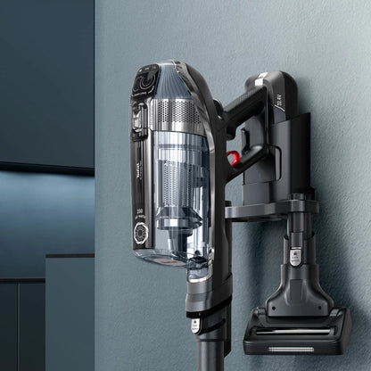 Front view of the Black & Grey Tefal X-Force Flex cordless stick vacuum mounted on its wall base with included pet accessories nearby.