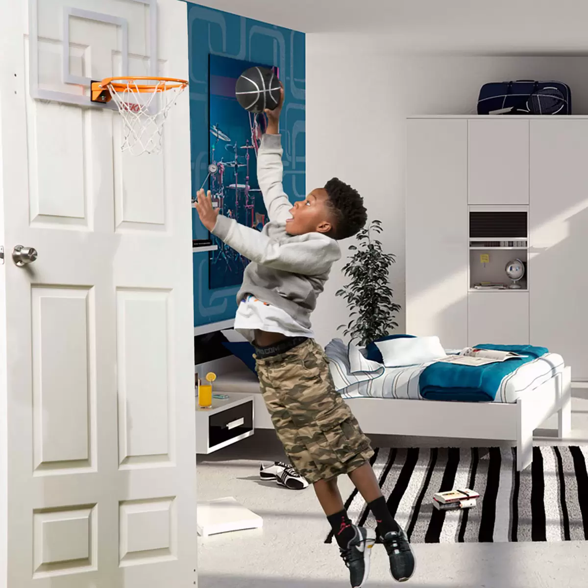 Close-up angled shot of the transparent Tekk Pro Mini Basketball Hoop mounted over a white door, showing the thick black foam backing pads and the bright orange steel breakaway spring rim.
