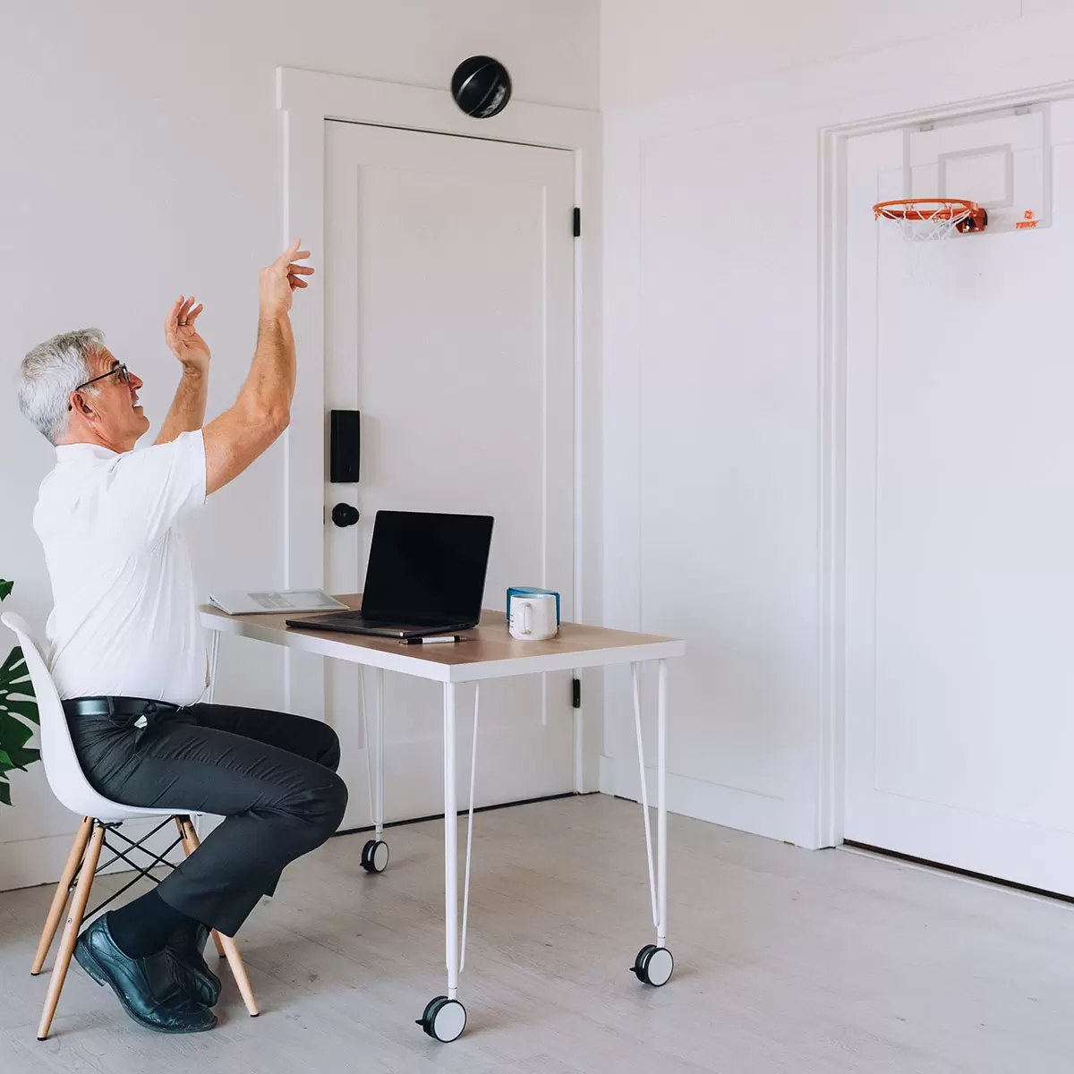 Close-up angled shot of the transparent Tekk Pro Mini Basketball Hoop mounted over a white door, showing the thick black foam backing pads and the bright orange steel breakaway spring rim.